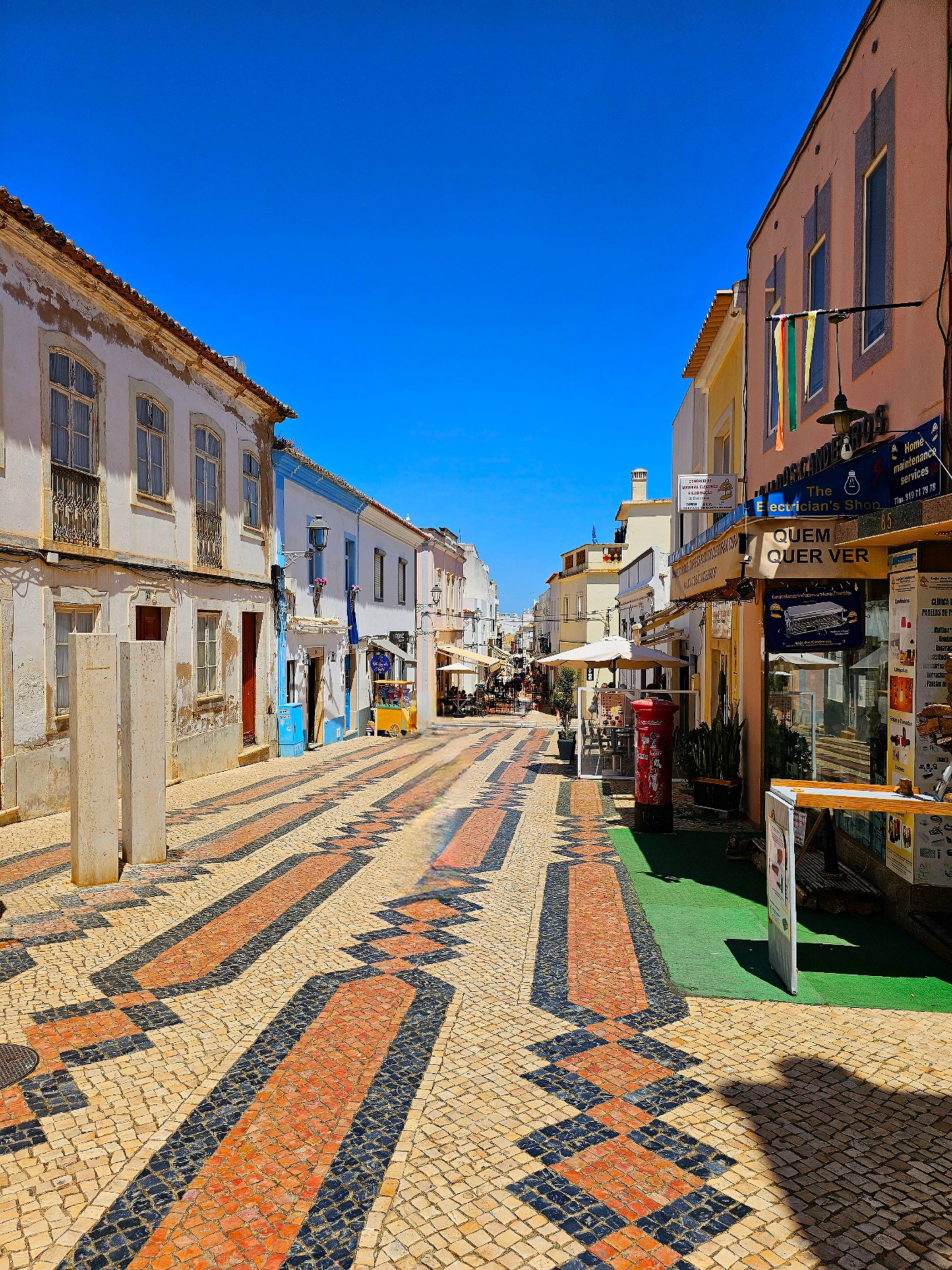 Narrow whitewashed street in a traditional Algarve town, where a small hire car makes driving easy